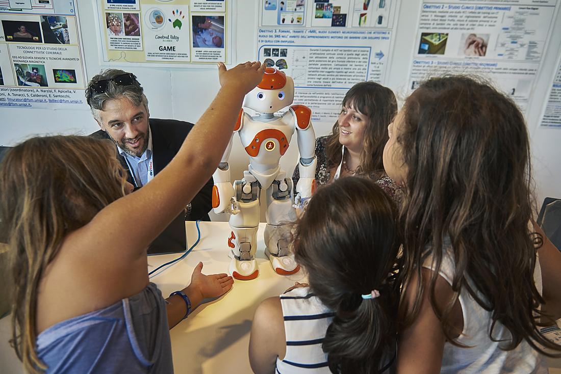 Children and a researcher interact with the NAO humanoid robot at the Festival della Robotica: an example of assistive and educational robotics for disability.